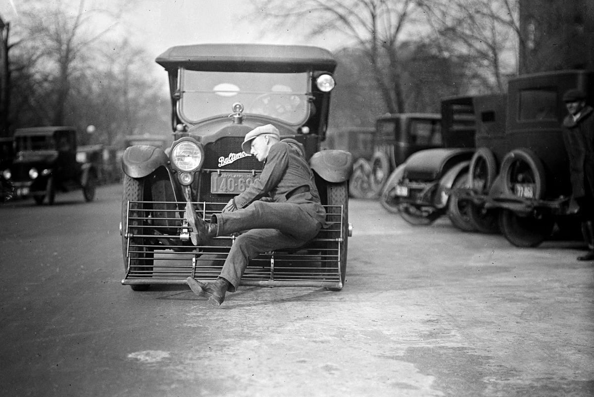 a man being collected by a cow catcher on the front of a car in 1924