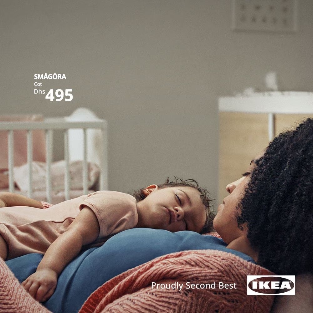 an Ikea ad with a baby sleeping on their mother's chest with a crib in the background